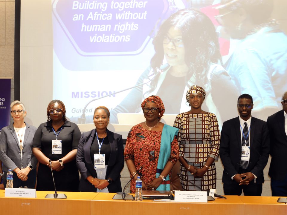 Panellists standing at the head table of the opening plenary of the NGO Forum, Banjul, May 2026